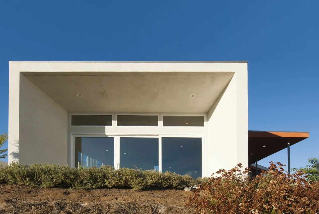 The Calle Anita house designed by MAKE Architecture features a minimalist front facade with a large glass sliding door and clerestory windows.