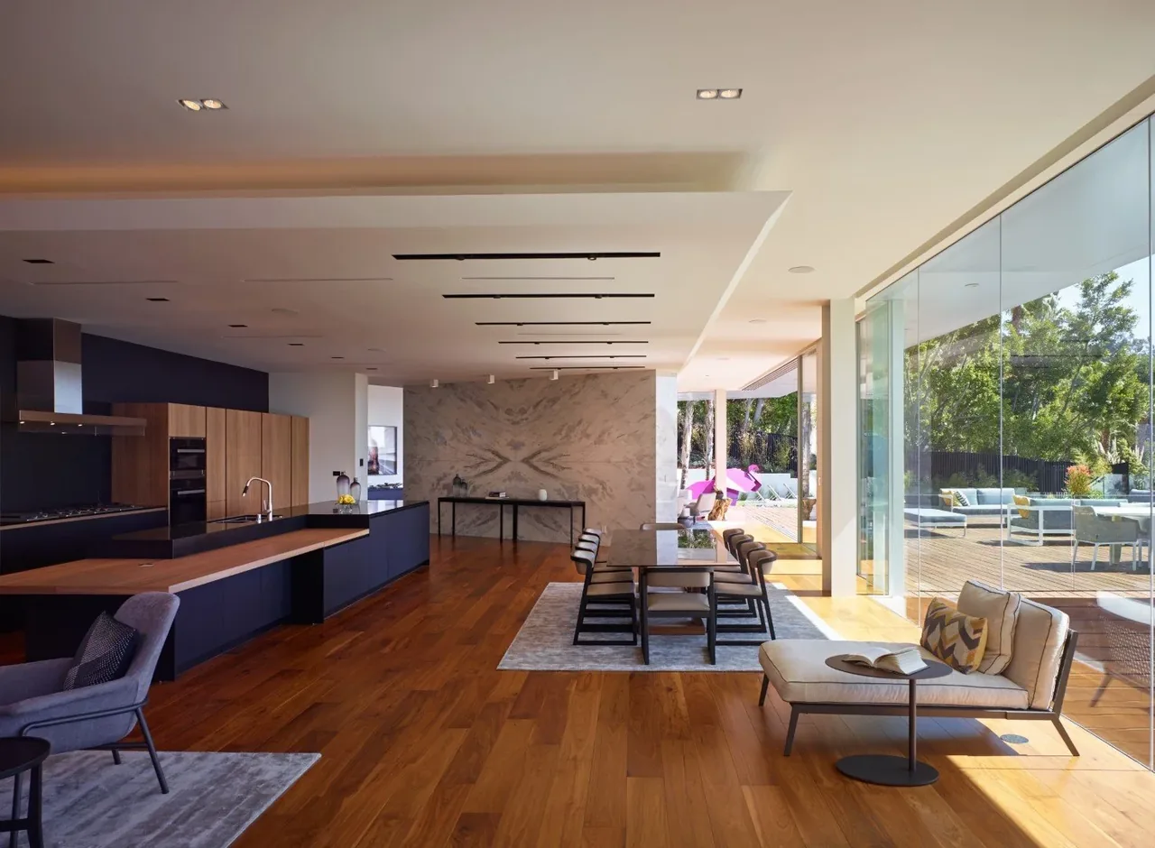 Open kitchen and dining room with a large marble accent wall and glass doors opening to the deck.