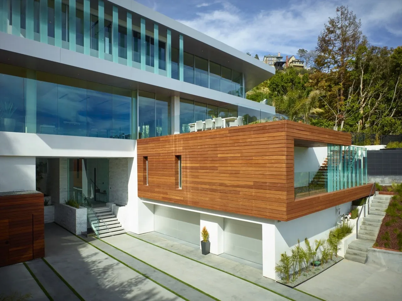 Rising Glen house features large glass windows and a wooden balcony on a hillside setting with city views.