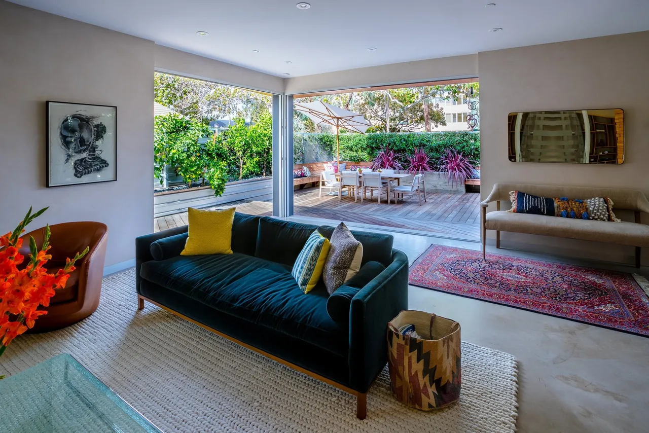 Living room opens via large sliding glass doors to a wooden deck with outdoor dining area and seating benches.