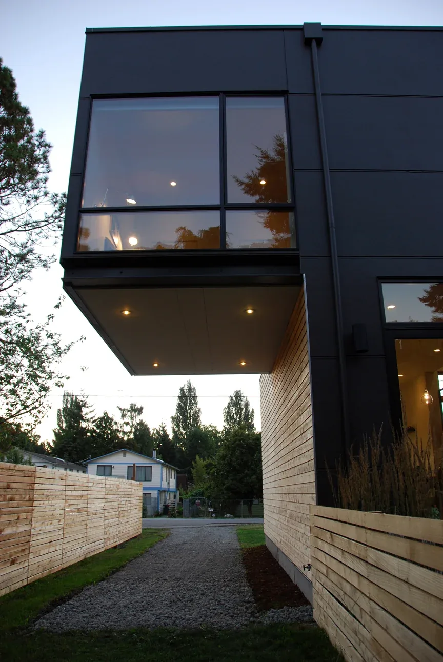 The Greenwood House features a cantilevered upper floor with black and wood exterior wall cladding.