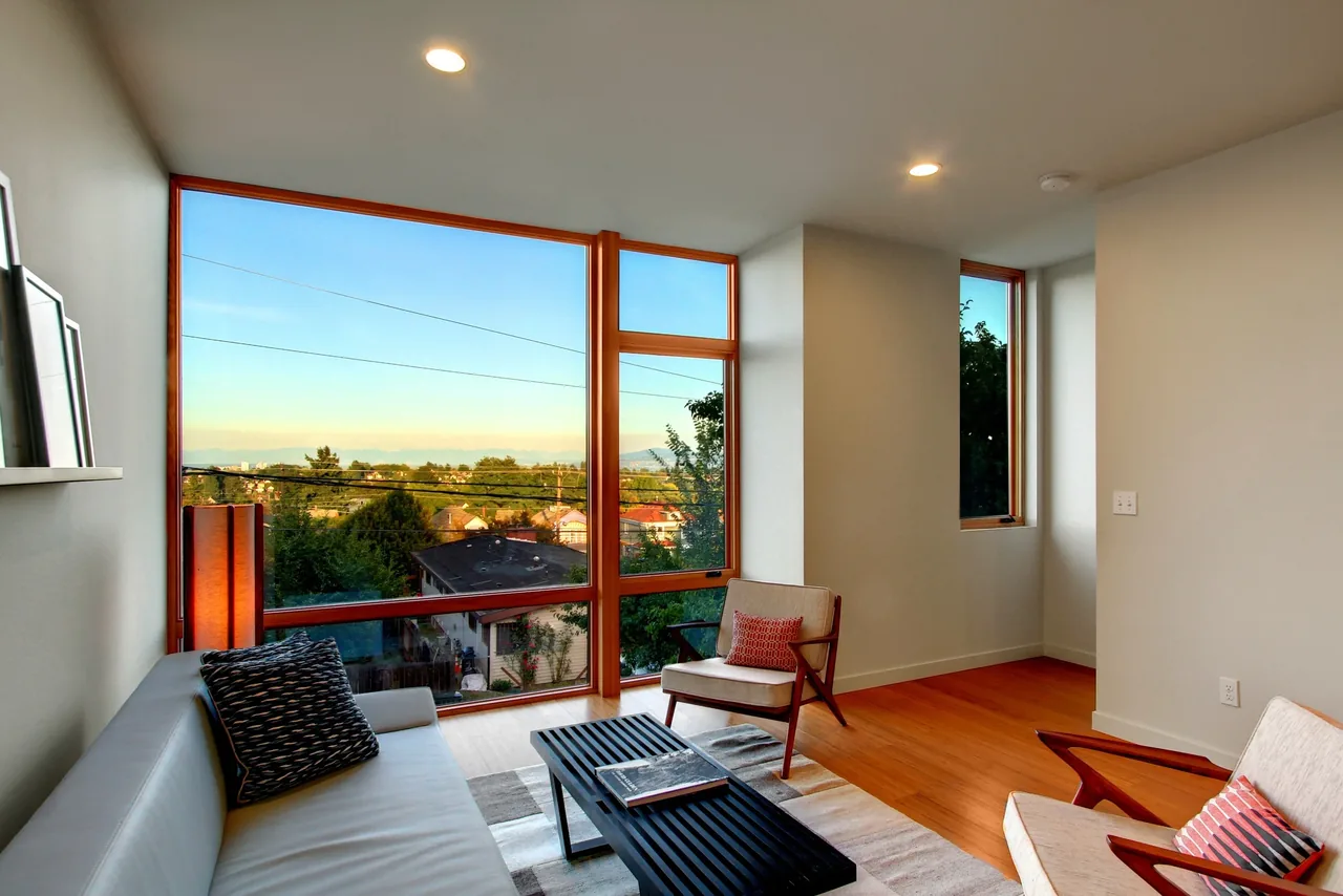 Living room with a large wood-framed window offering expansive views of the surrounding neighborhood.