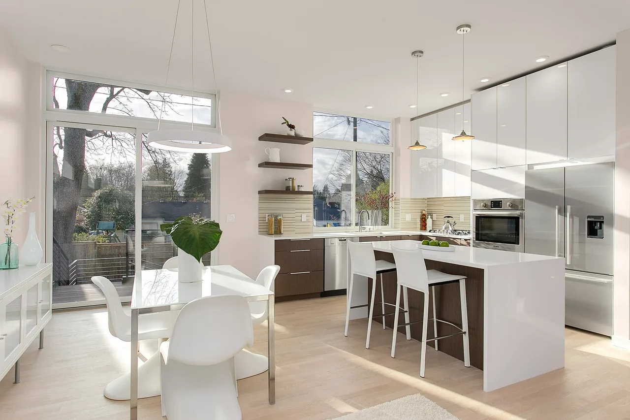 The Wedgwood project features a bright kitchen with white cabinetry, a kitchen island, and floor-to-ceiling sliding glass doors to the deck.