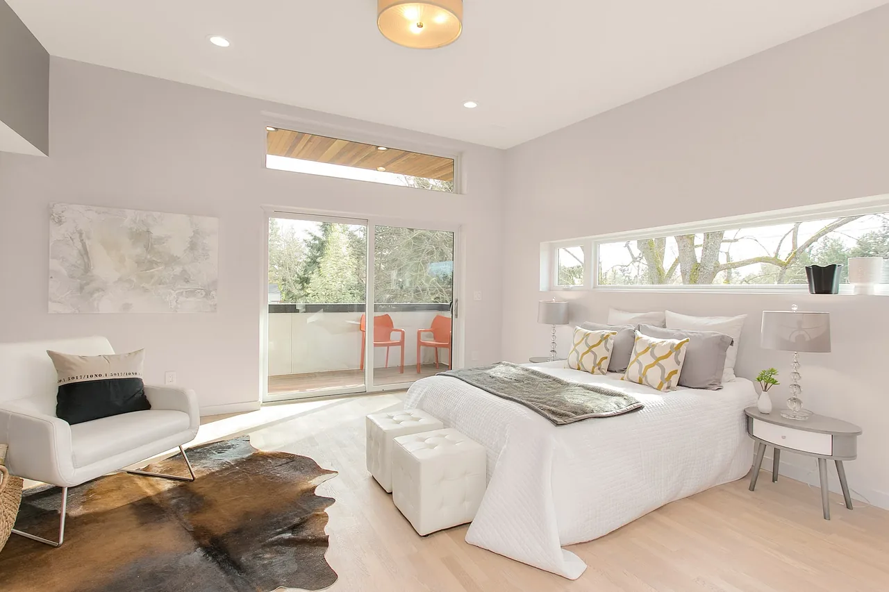 The Wedgwood bedroom by Malboeuf Bowie Architecture features a light-filled space with sliding glass doors to an outdoor deck and modern furnishings.