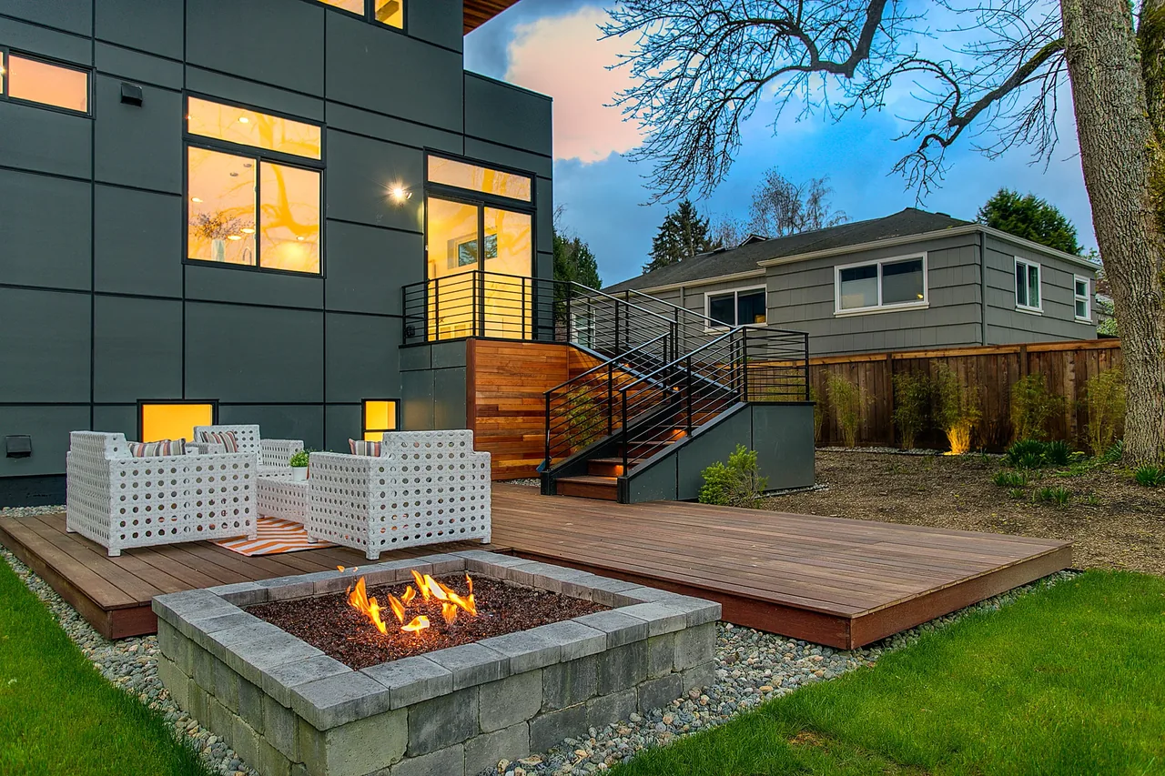The Wedgwood features a raised wood deck with metal railings and a stone fire pit in the backyard courtyard area.