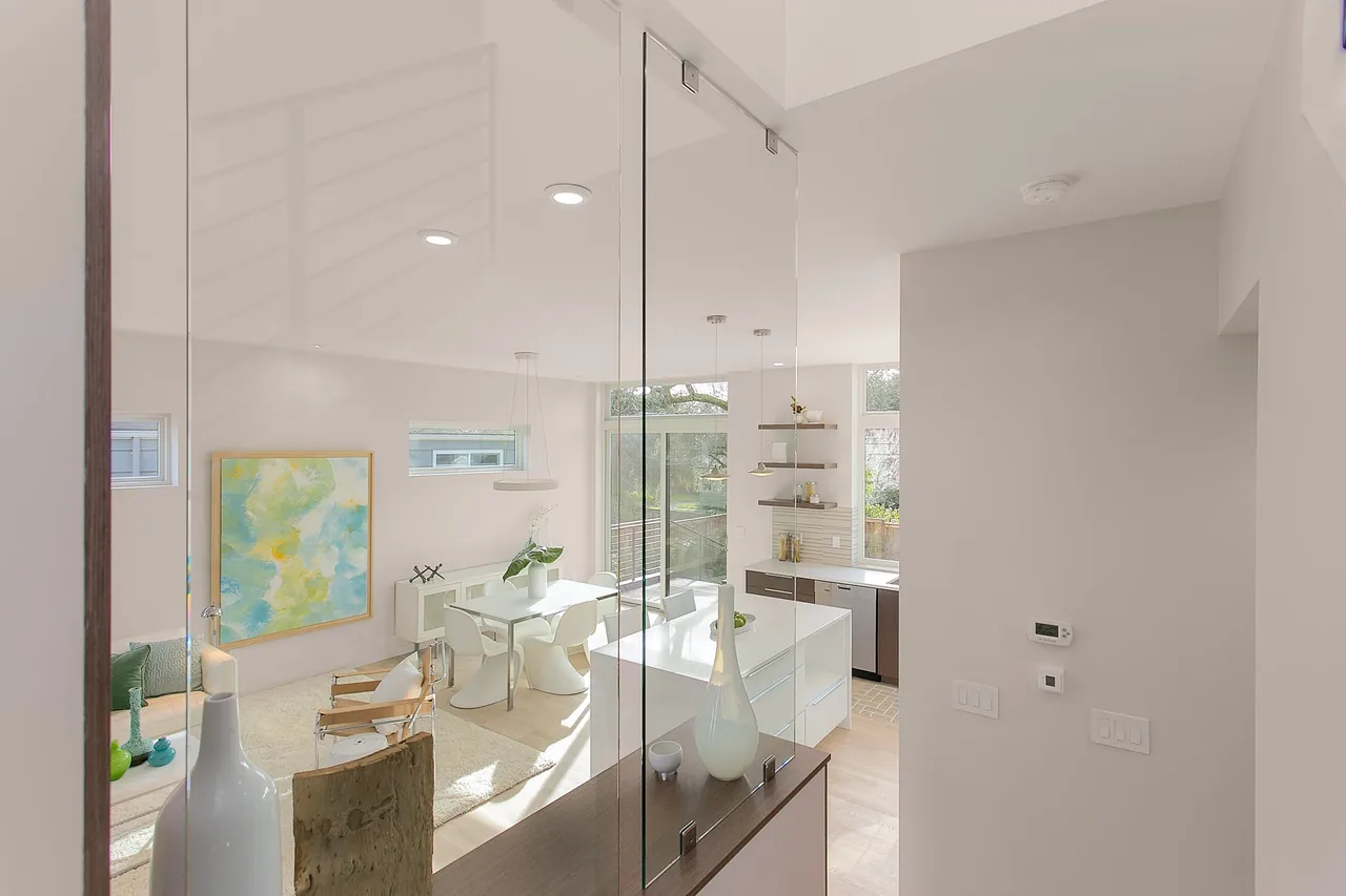 Modern open living and kitchen with glass divider and natural light in The Wedgwood project.