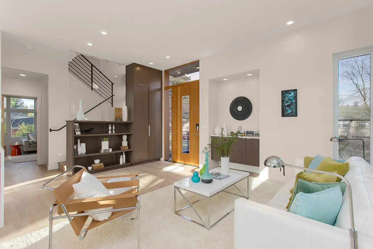 The Wedgwood living room features modern design with light wood flooring and a large wooden front door with glass panels.