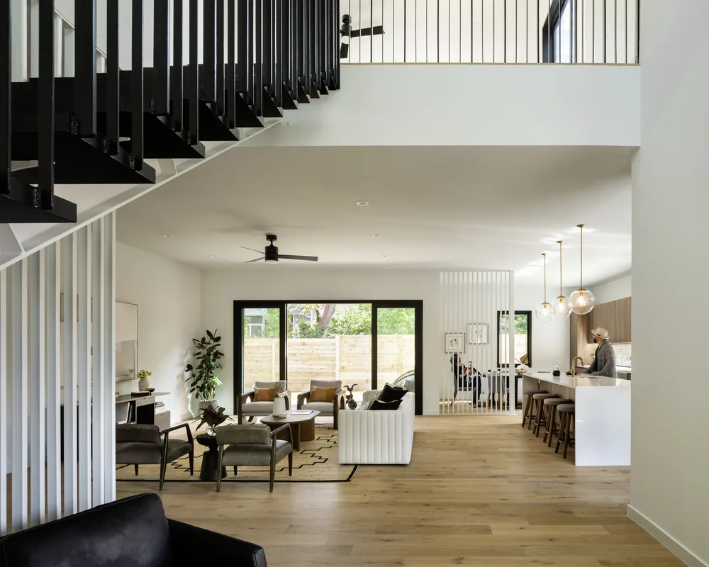 The Bull Creek project features an open living room and kitchen with black window frames and a modern staircase design.