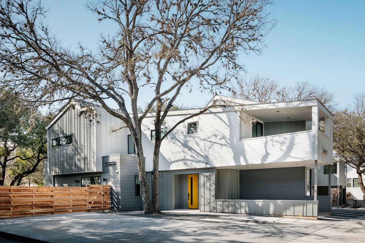 Clawson Duplexes show a modern two-story design with metal siding, a bright yellow door, and a sloped roof.