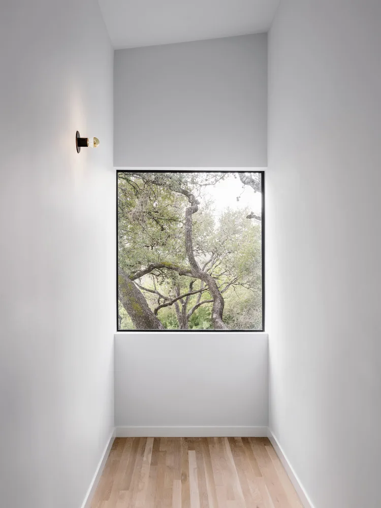 A narrow hallway with a large picture window framing tree branches in the Clawson Duplexes project.