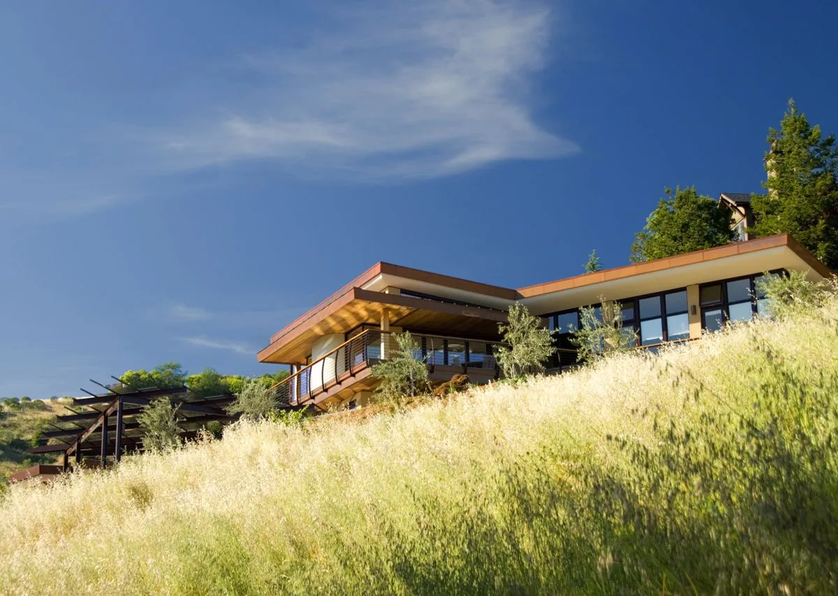 Mill Valley home featuring flat roof, extensive glazing, and an outdoor balcony above hillside vegetation.