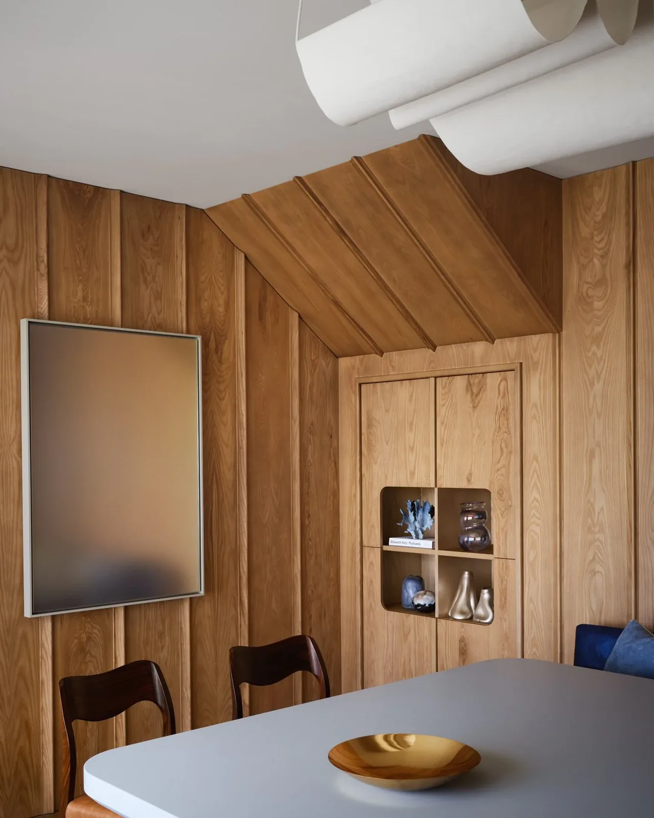 Dining area with integrated wood-paneled shelving and sculptural decor at Pacific Promontory.