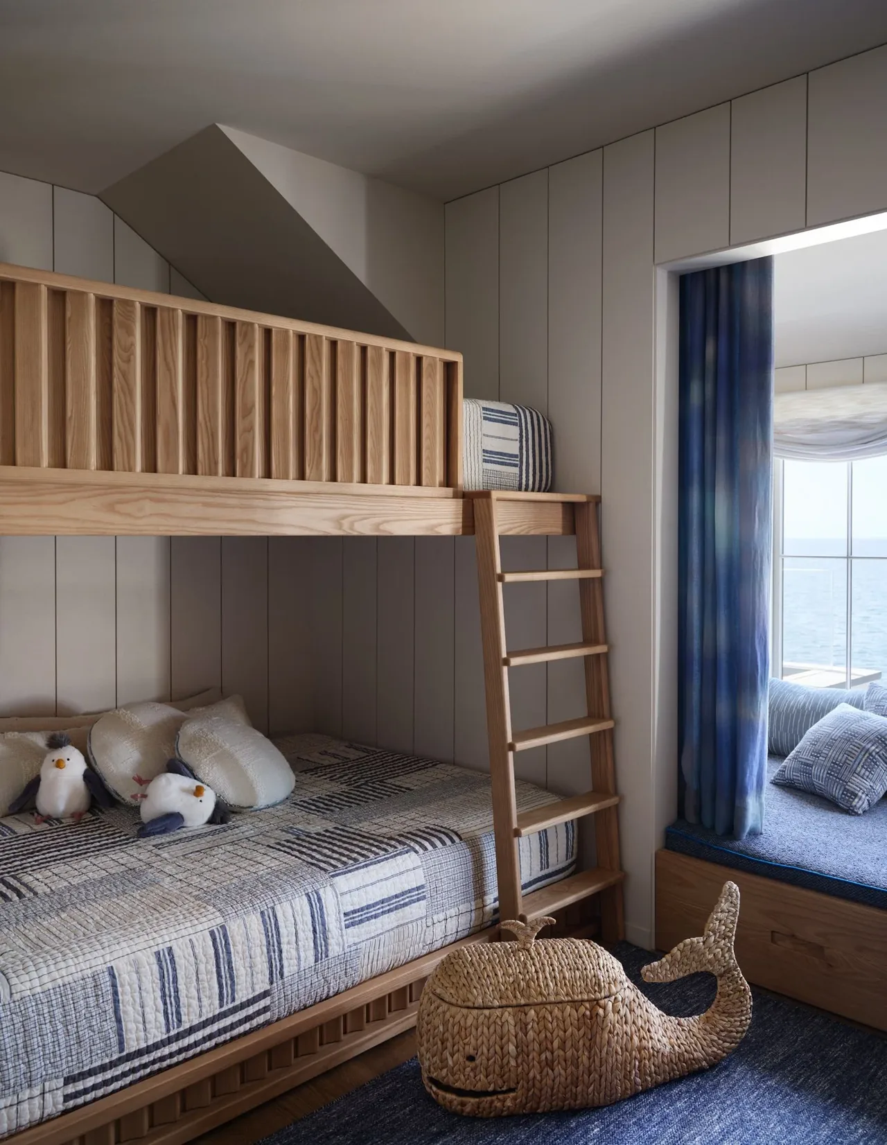 Children's bedroom with wooden bunk beds and a window seat overlooking the ocean at Pacific Promontory.