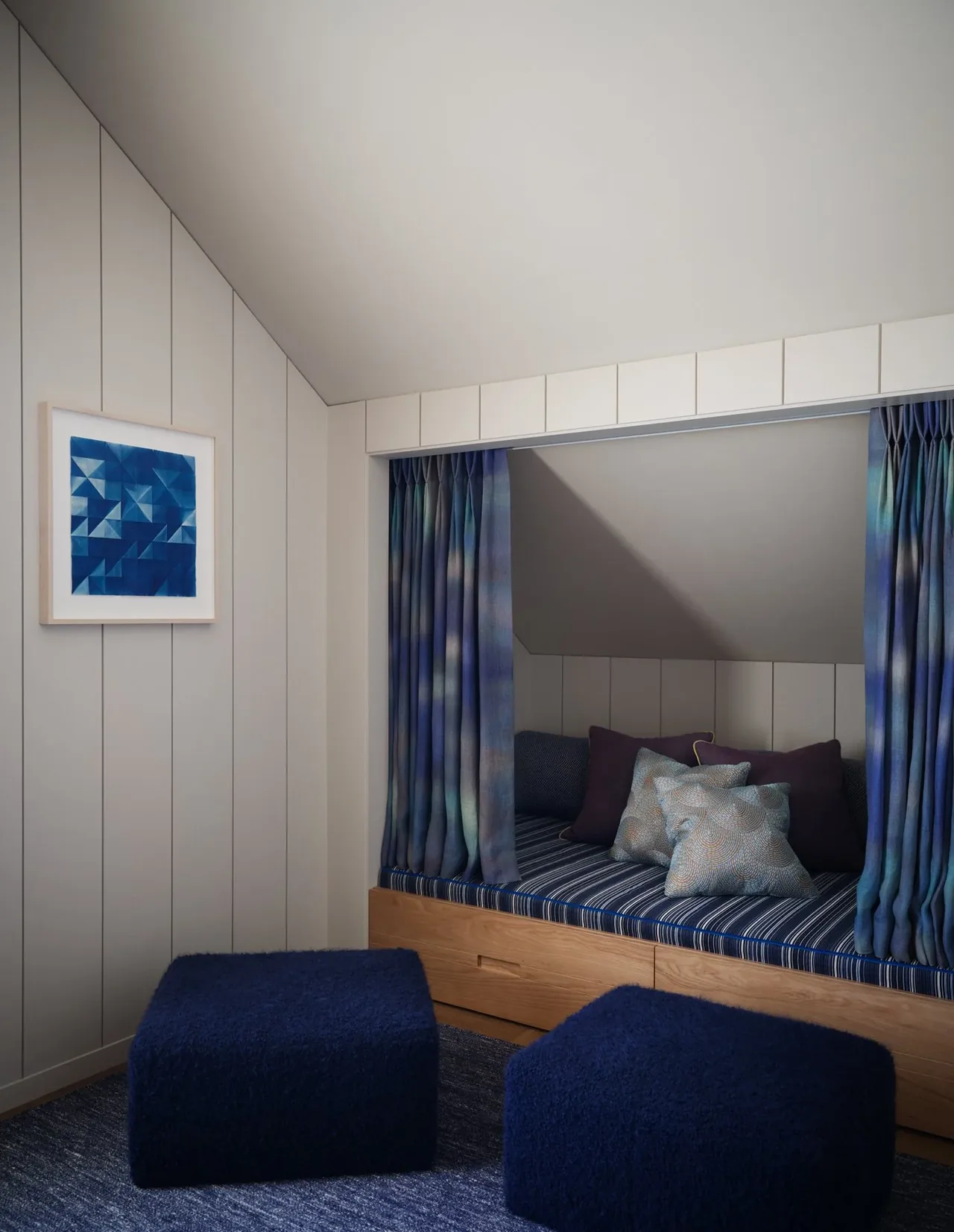 Built-in seating nook with striped cushions and blue curtains in a softly lit cozy corner space.