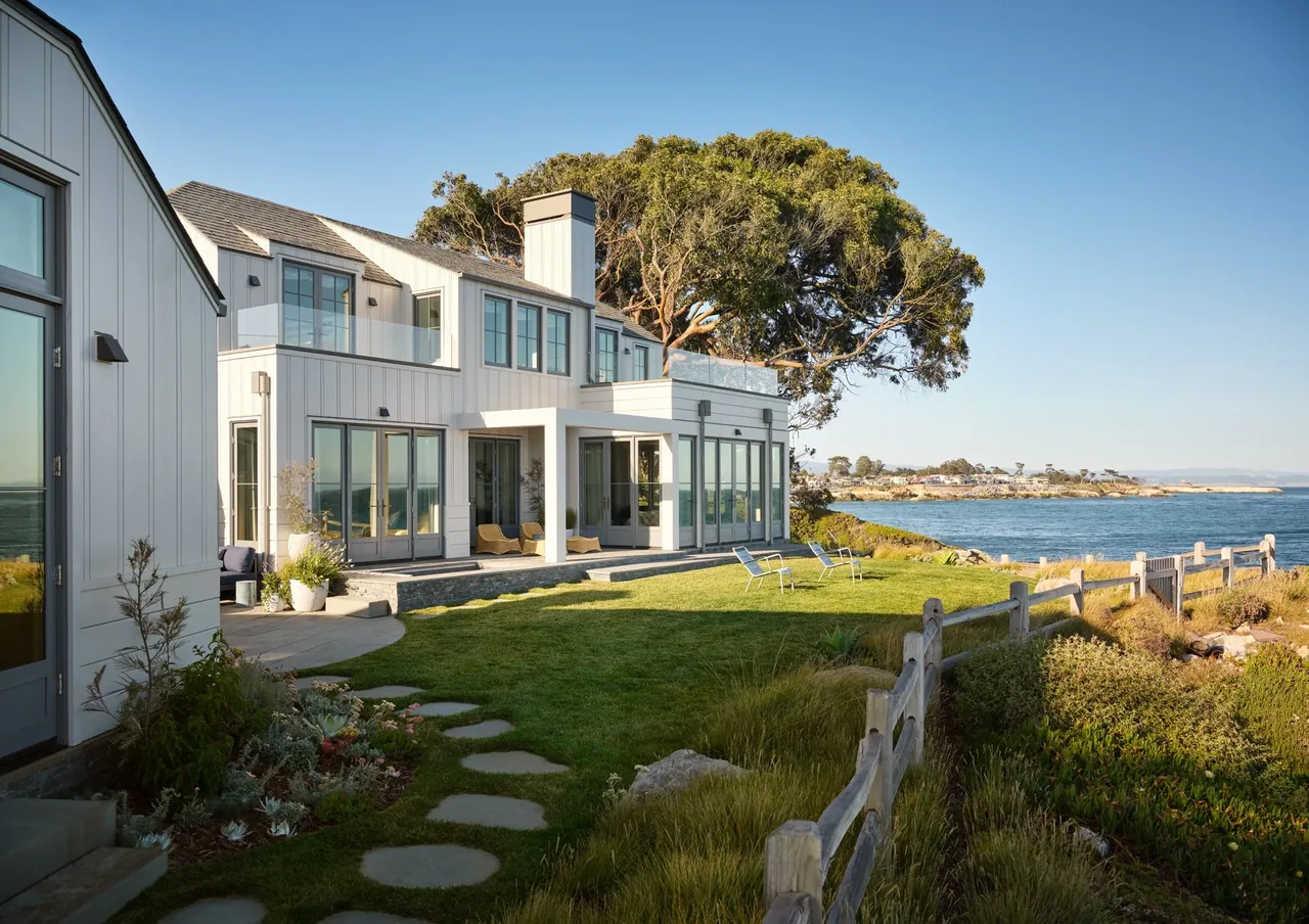 The Pacific Promontory project features a white two-story home with large windows and ocean views in a coastal setting.