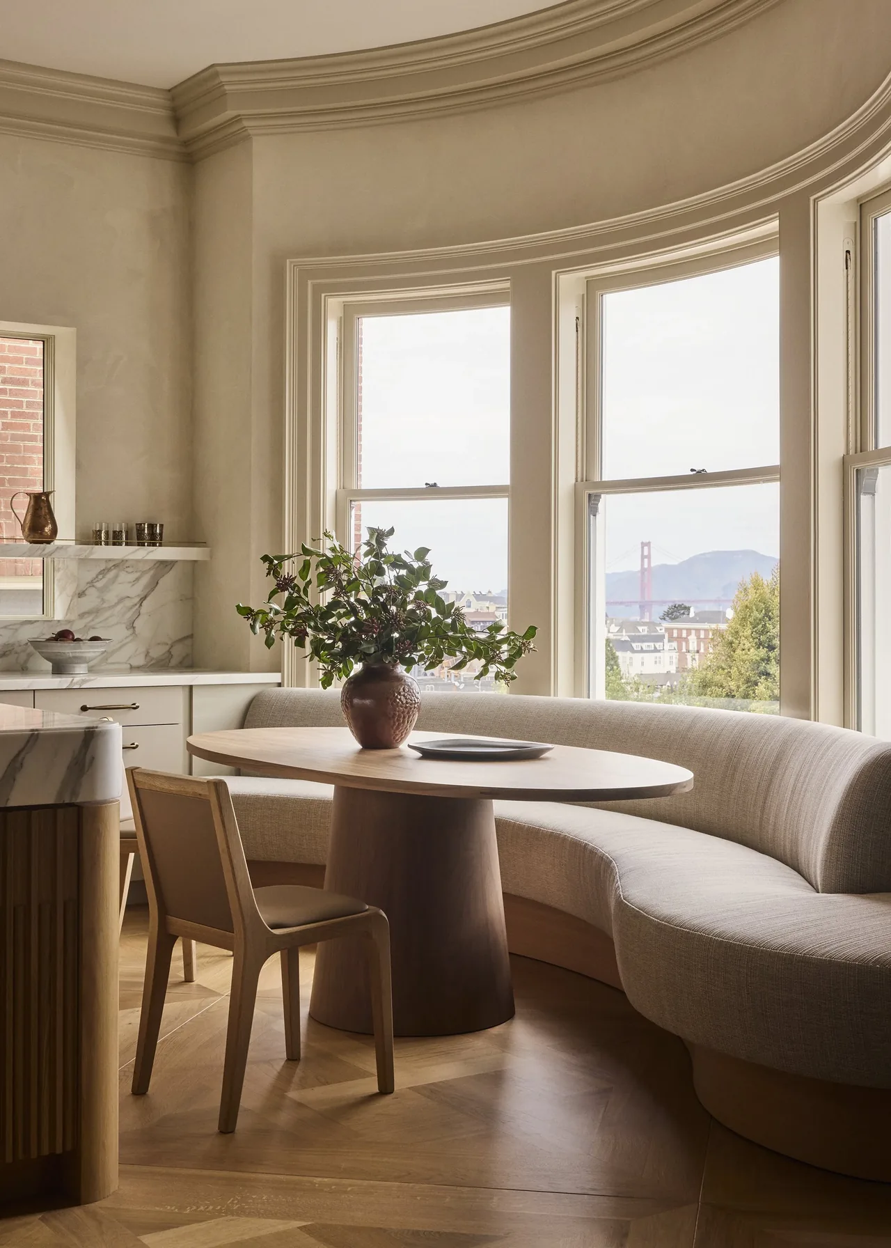 Dining nook with a curved banquette and round wooden table overlooking the city and Golden Gate Bridge.
