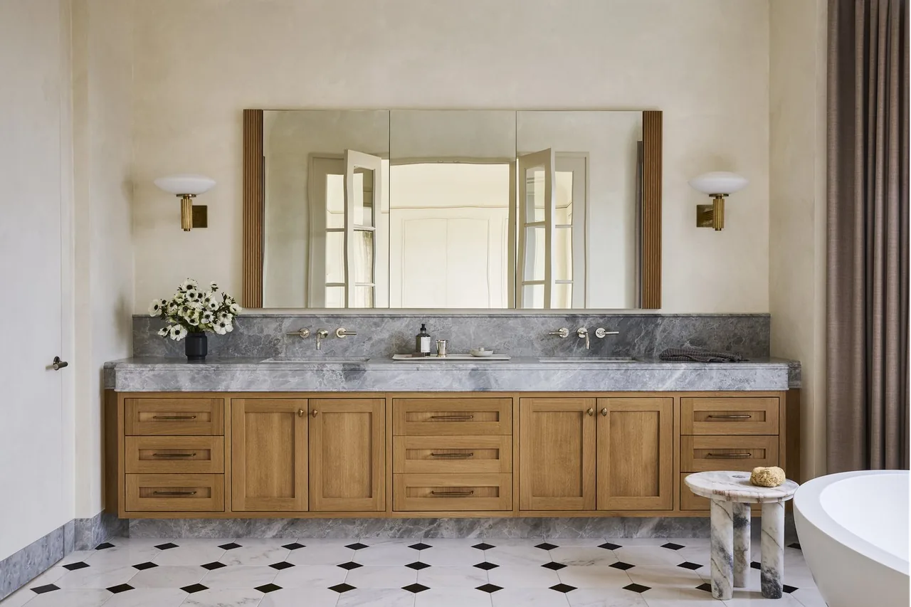 Modern Georgian bathroom features a wide double vanity with wood cabinets and a marble countertop beneath a large mirror.