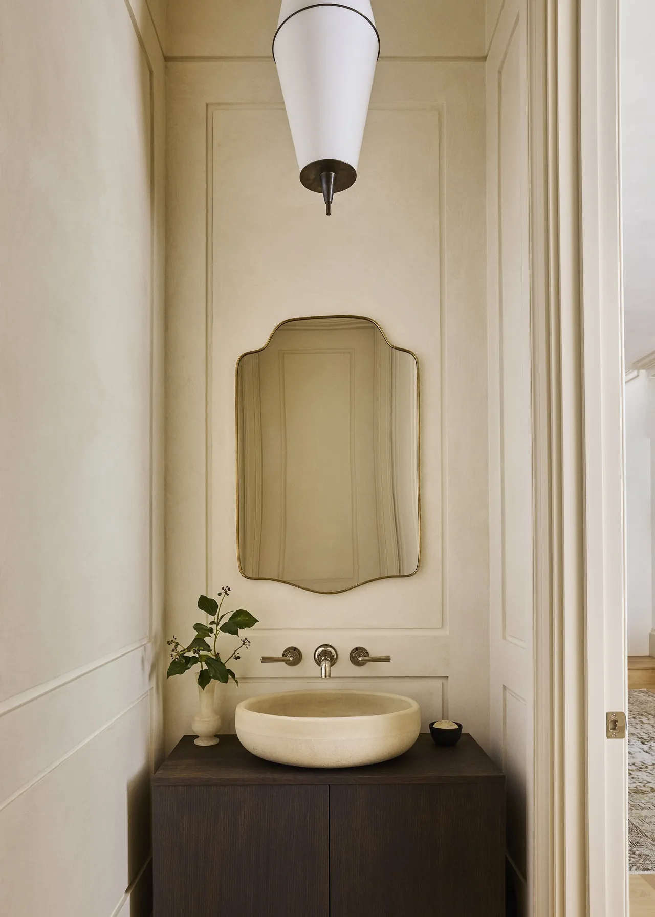 Bathroom vanity with a round stone sink, custom mirror, and contemporary pendant light fixture.