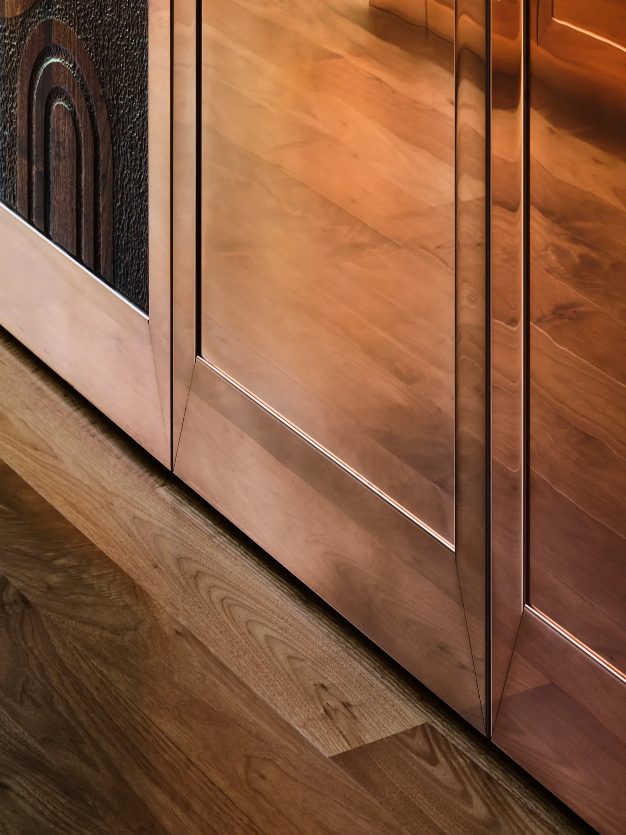 Copper cabinetry with textured wood panels and polished copper doors on wood flooring in the Gallery House project.