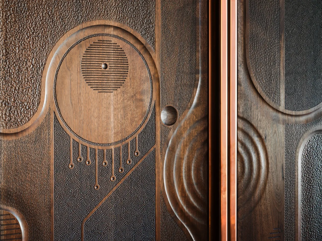Carved wooden cabinet doors featuring detailed textured patterns and round copper handles.