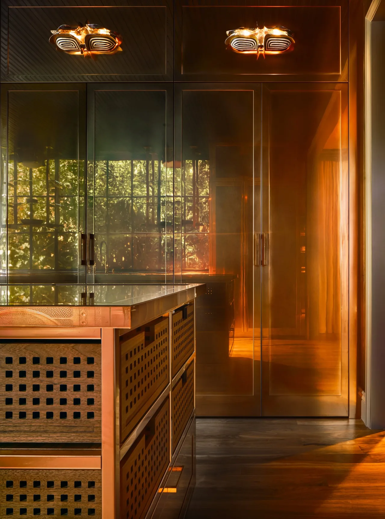 Copper finished cabinetry and reflective copper doors create a warm kitchen space in the Gallery House project.
