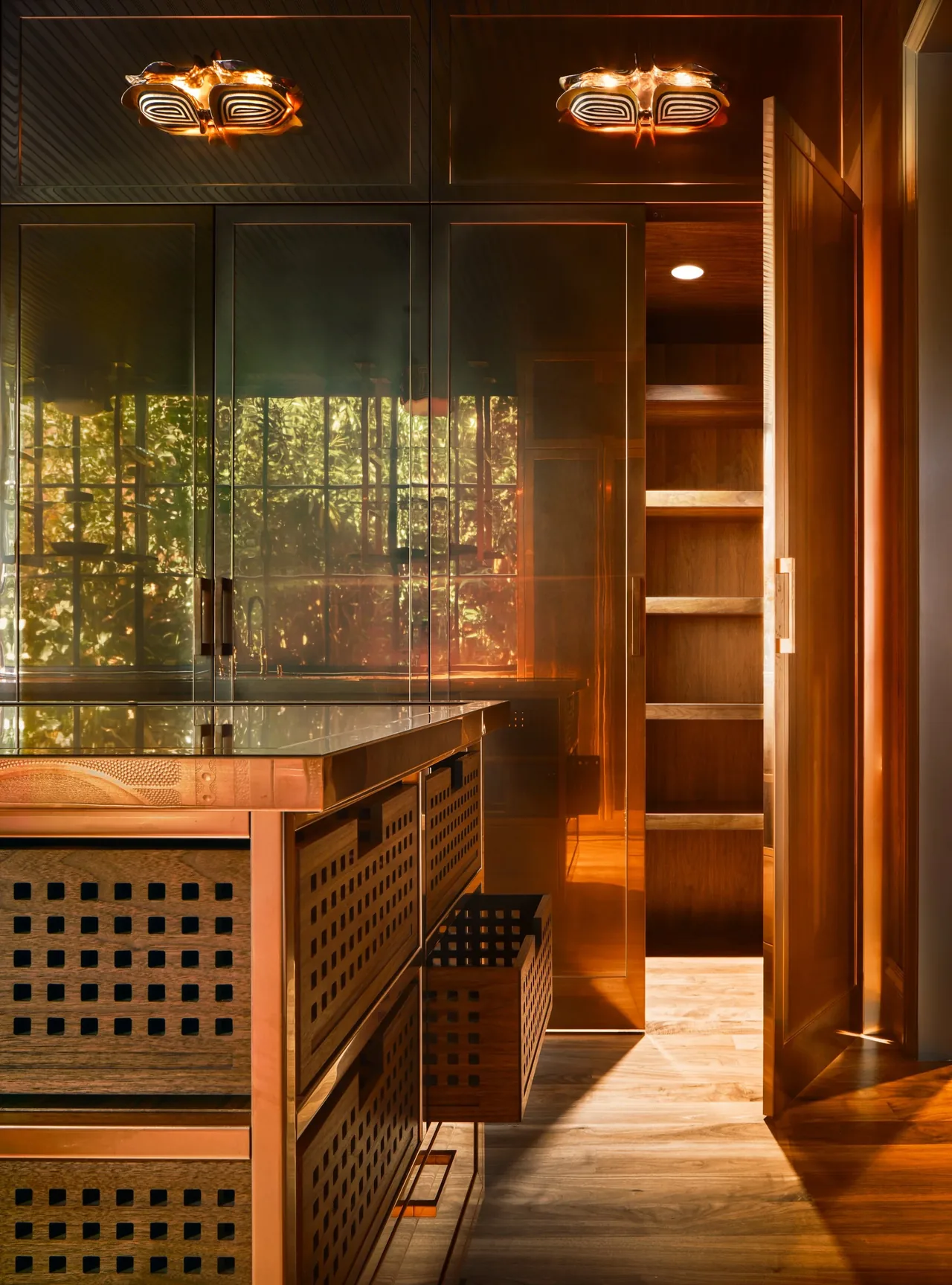 The Gallery House kitchen showcases copper finish cabinetry with patterned wood drawer fronts and a stone countertop.