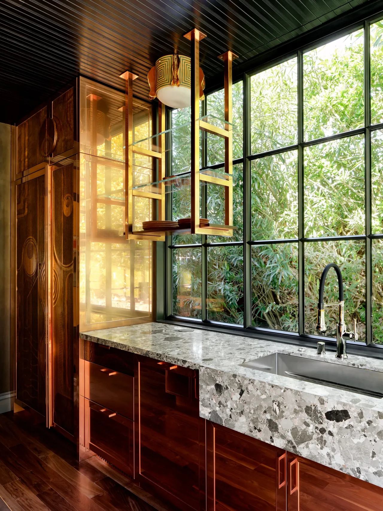 Gallery House kitchen features a marble countertop with copper cabinetry beneath expansive black-framed grid windows.