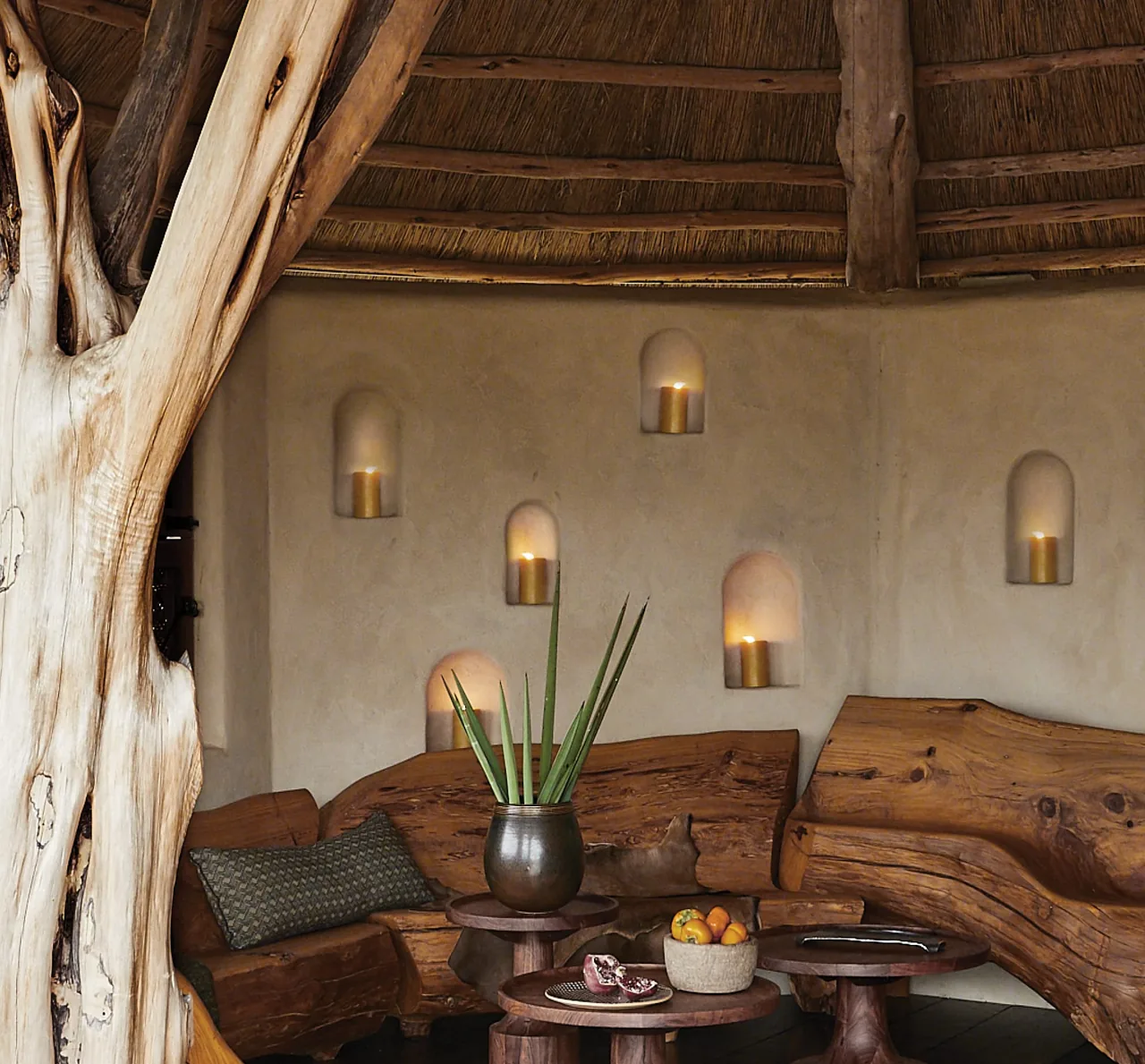 The Rancho Sabino Grande round hut features natural branch posts, rustic wooden benches, and built-in wall niches with candles.