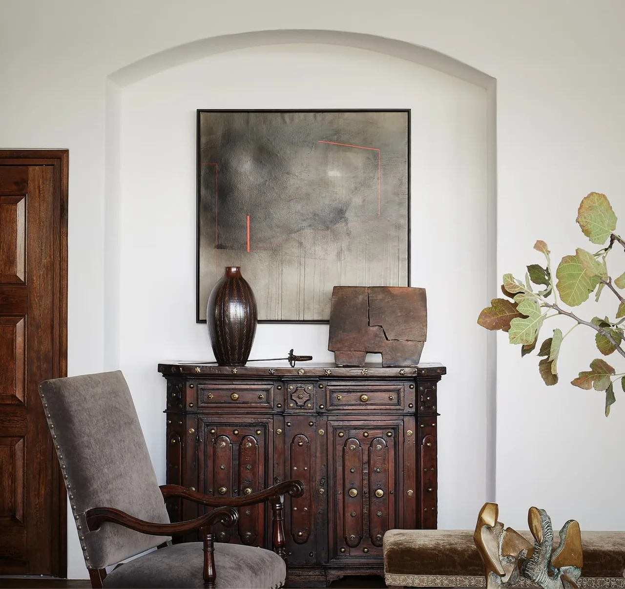 Rancho Sabino Grande features an antique-style wooden cabinet beneath abstract wall art and an arched niche above.