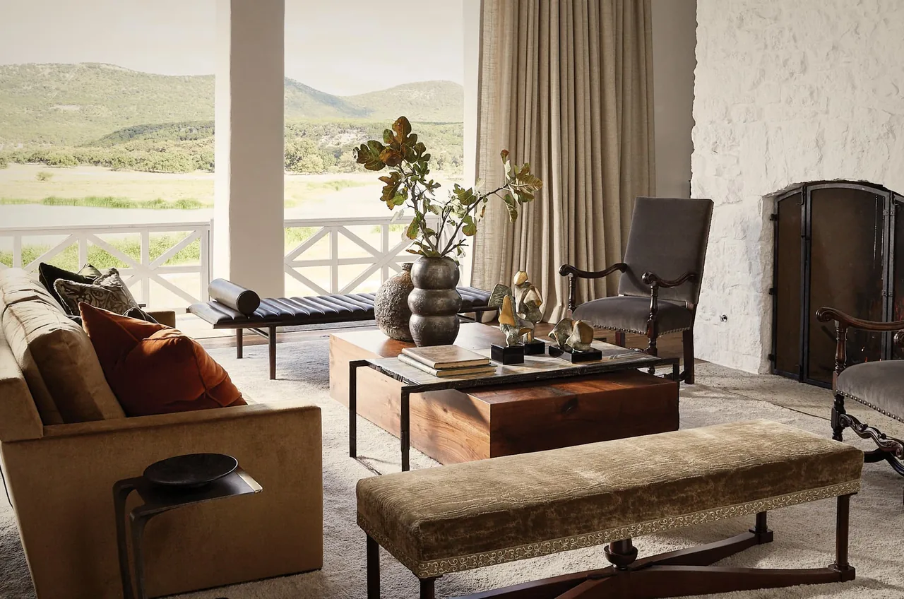 Living room in Rancho Sabino Grande with a stone fireplace and large windows framing hillside views.