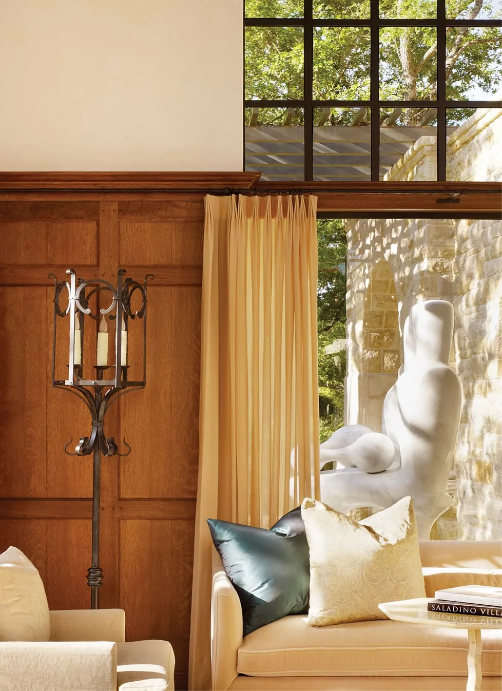 Turnberry project living area with wood paneling, cream curtains, and a view of a stone sculpture through a divided lite window.