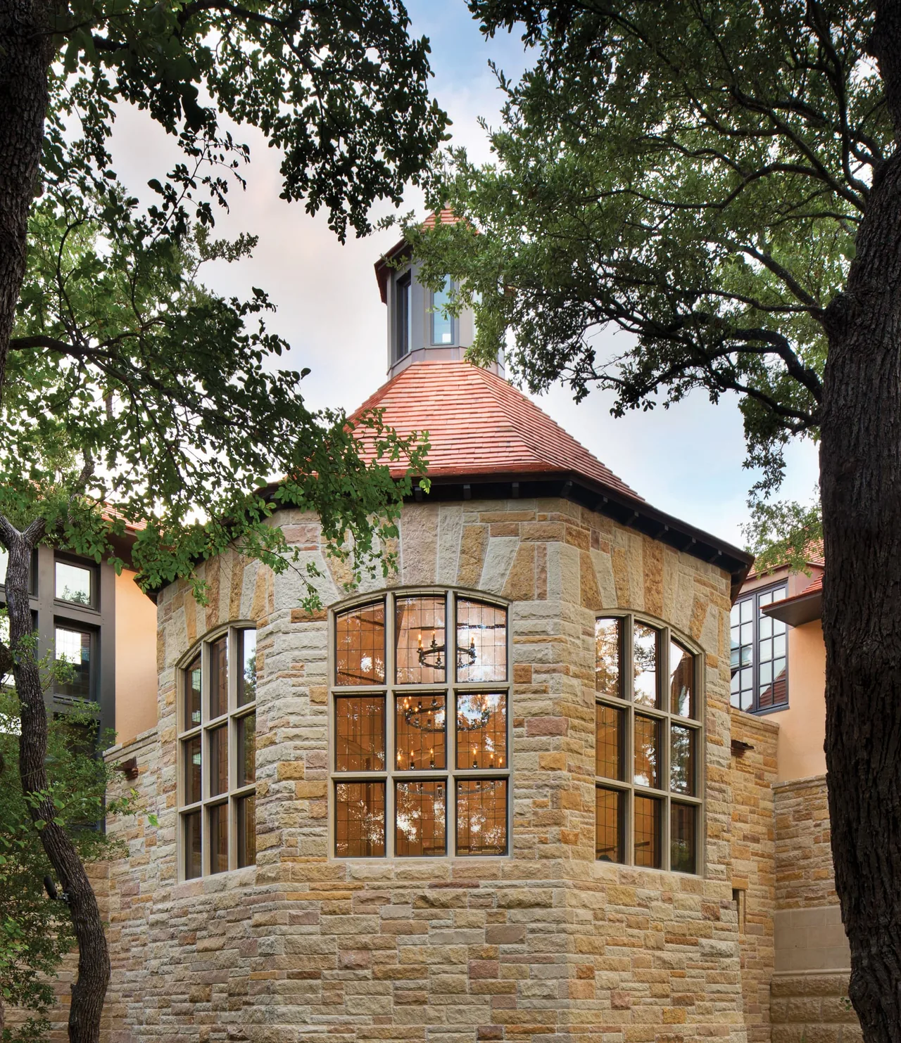 Stone exterior with large framed windows and a terracotta red roof on a multi-level house.