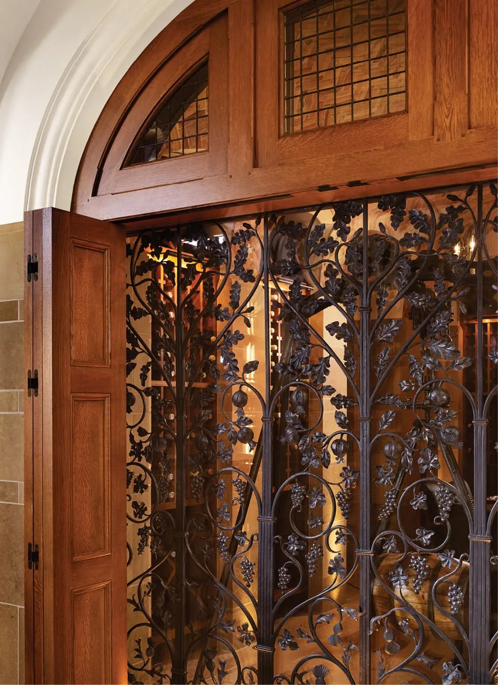 Decorative wrought iron gate with grapevine motifs set within an arched wooden frame.