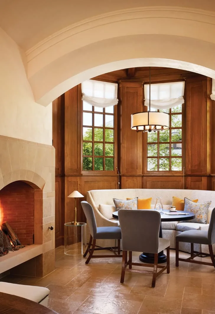 Turnberry project features a cozy dining nook with a stone fireplace and wood-paneled arched windows.