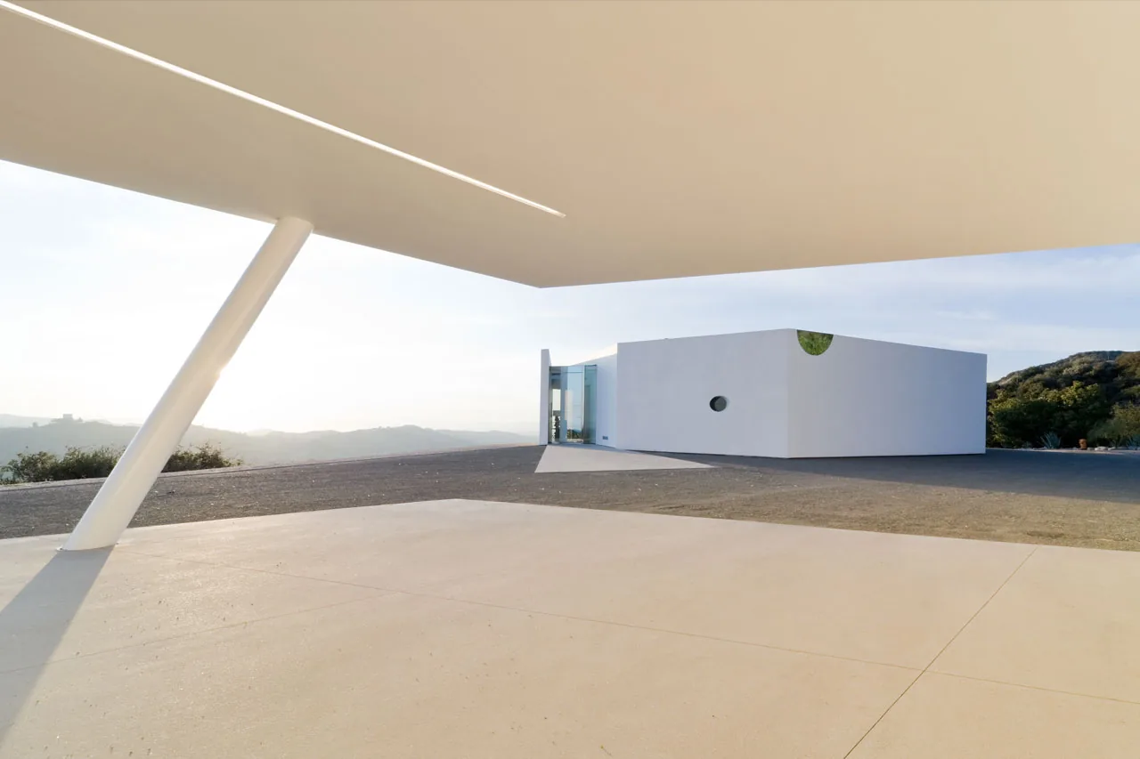 Pittman Dowell residence by Michael Maltzan Architecture features a minimalist white cubic form with circular windows and an angled overhang.