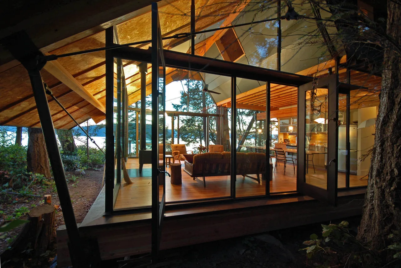 The glass cabin designed by zeroplus features floor-to-ceiling glazing and an open ceiling structure, blending indoor and outdoor living.