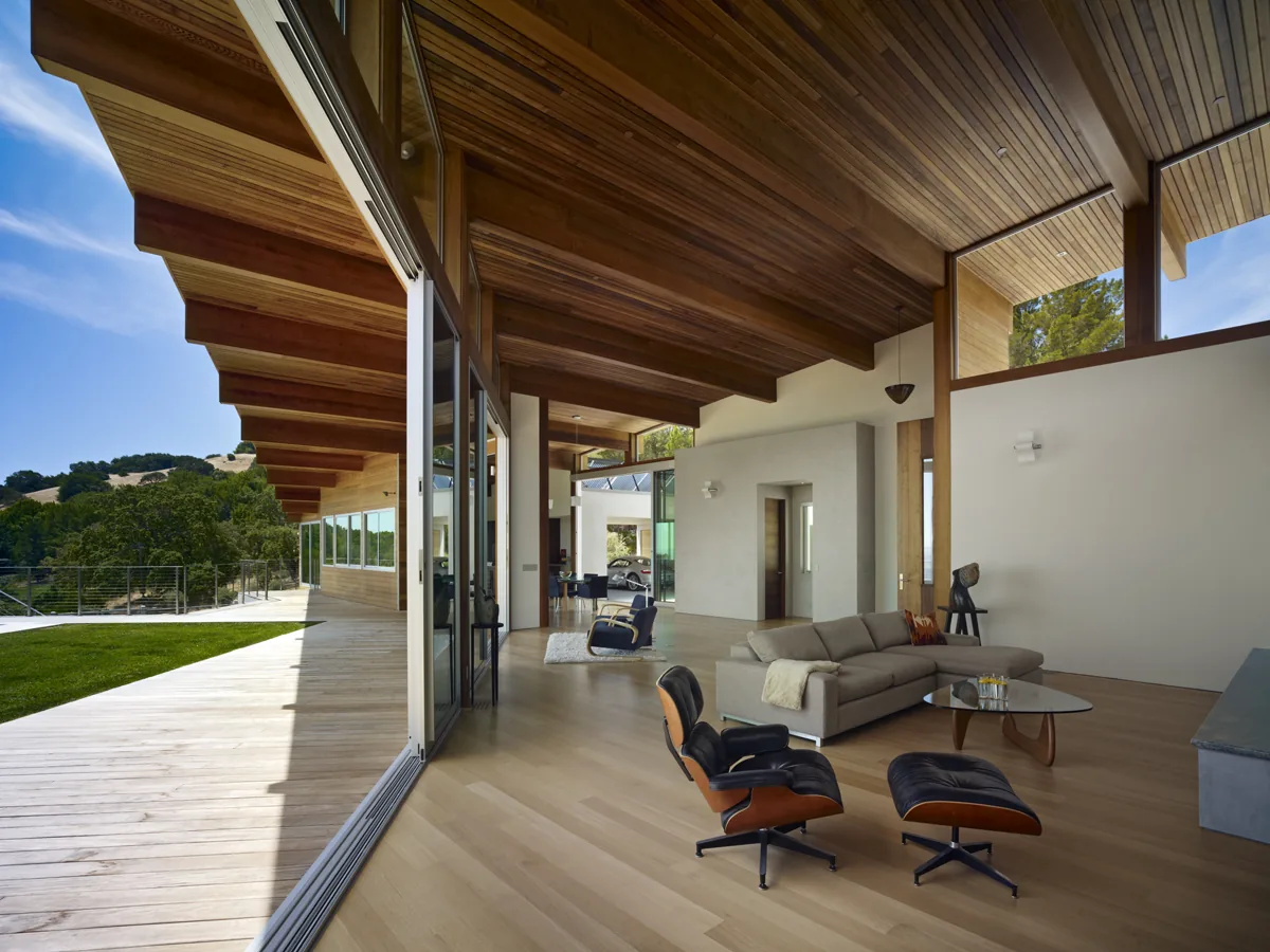 Living area with wood-paneled vaulted ceiling opens to outdoor deck via large sliding glass door in vistadelvalle project.