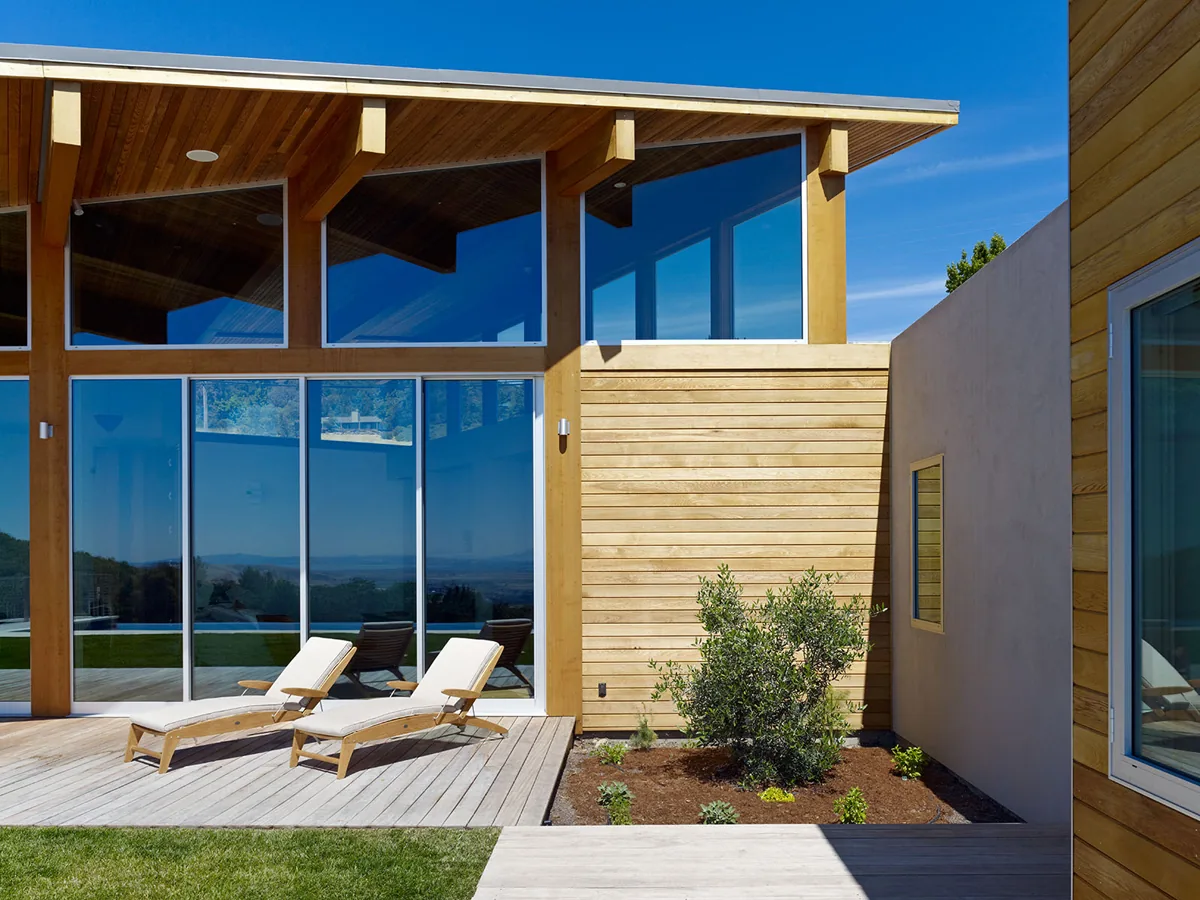 Modern home exterior featuring large floor-to-ceiling windows and wood siding at vistadelvalle by Zimmerman + Associates.