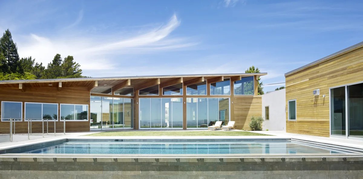 Vistadelvalle project features wood siding, floor-to-ceiling glazing, and a flat roof beside a swimming pool.