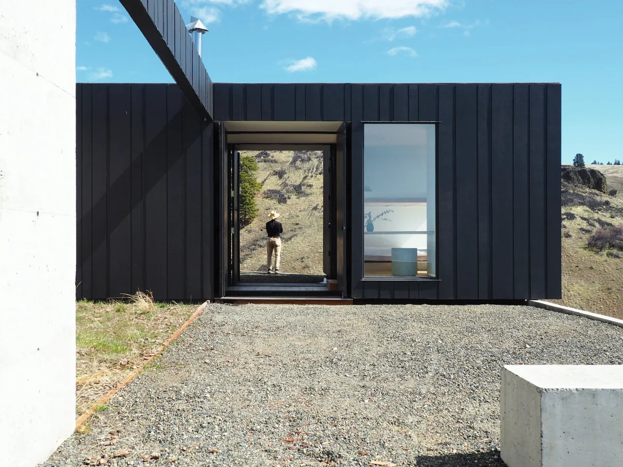Basalt Canyon Shelter by Workshop A | D features black vertical panel siding with expansive glazing and open passageways.