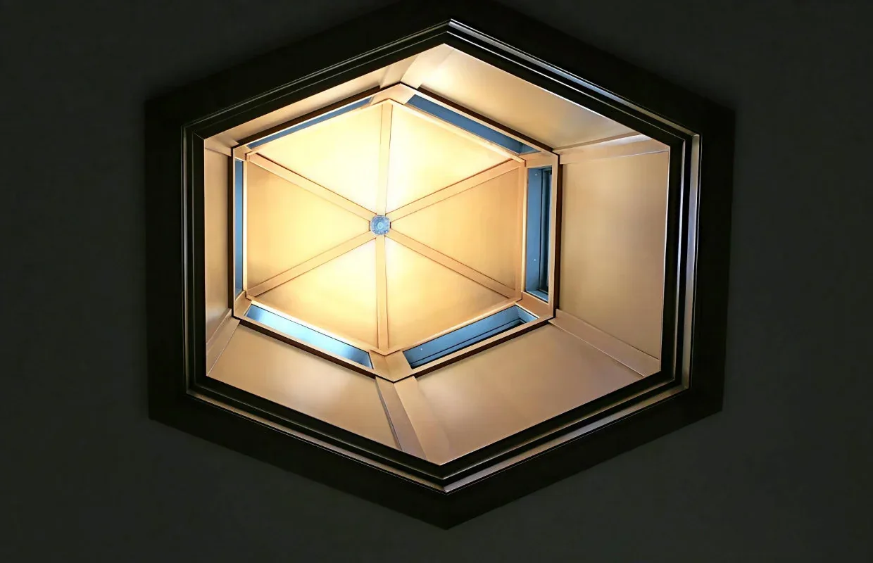 Ceiling view of a hexagon-shaped skylight featuring geometric framing and translucent glass panels.