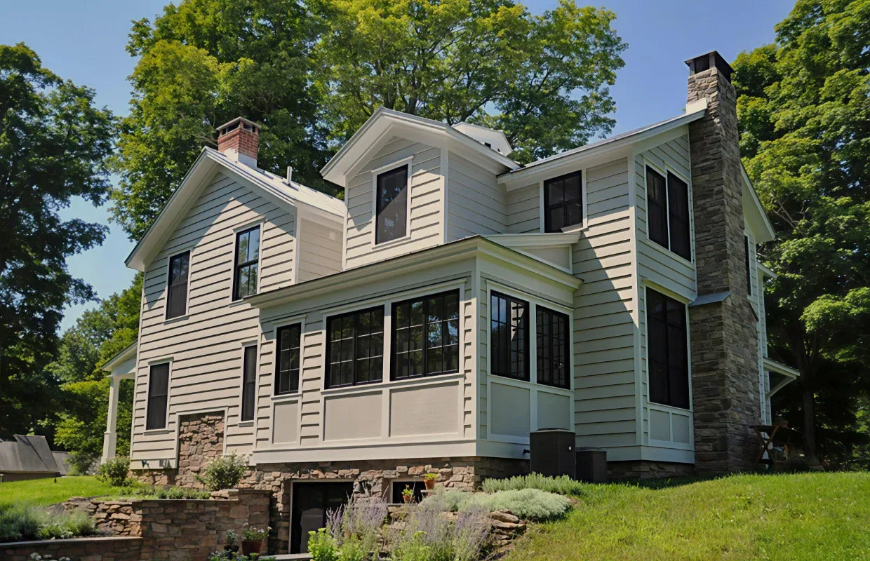 Hudson Valley home featuring white wood siding, black multi-pane windows, a brick chimney, and stone foundation details.