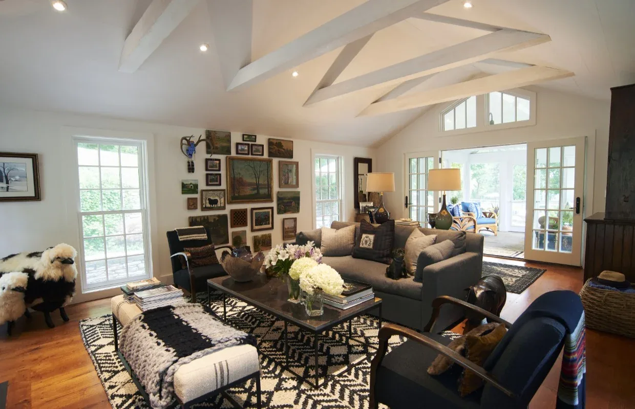 Living room in Frog Pond Farm features vaulted ceiling with exposed beams and double glass doors leading outdoors.