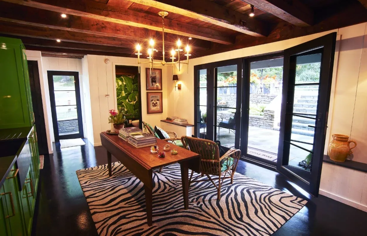 Interior room with wood beam ceiling, green cabinetry, and black-framed glass doors leading outdoors at Frog Pond Farm.