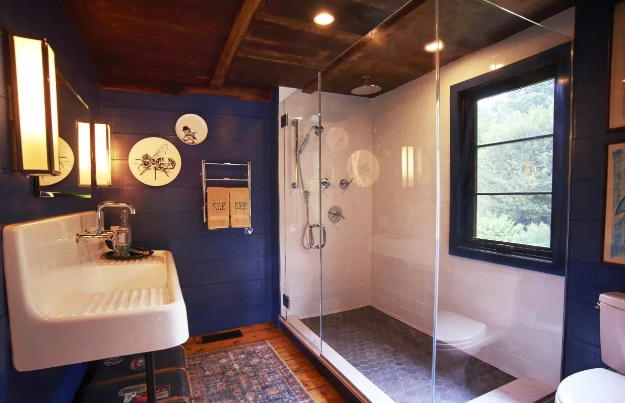 Bathroom features a glass shower with white subway tiles, hexagonal floor tiles, and a wall-mounted sink with modern fixtures.