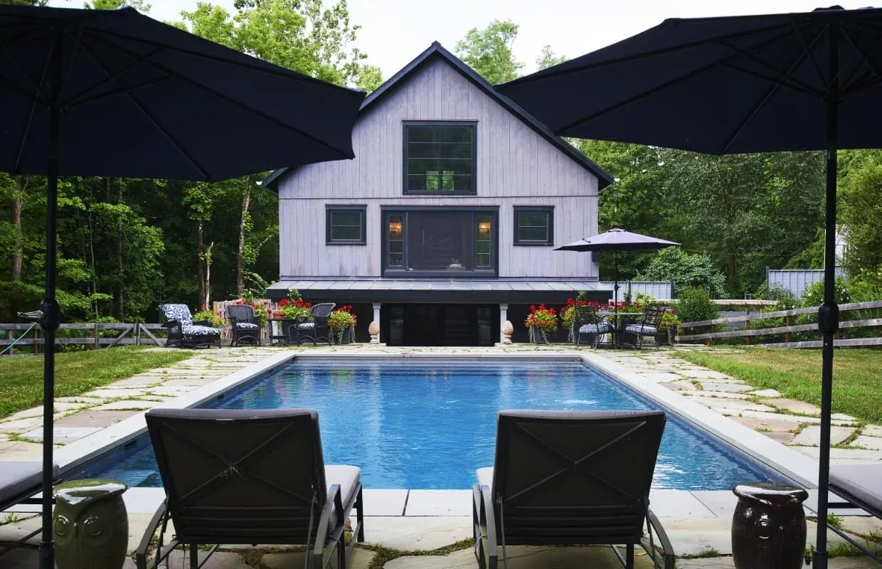 FROG POND FARM features a gable-roofed modern farmhouse exterior with white wood siding and a rectangular pool in the backyard.
