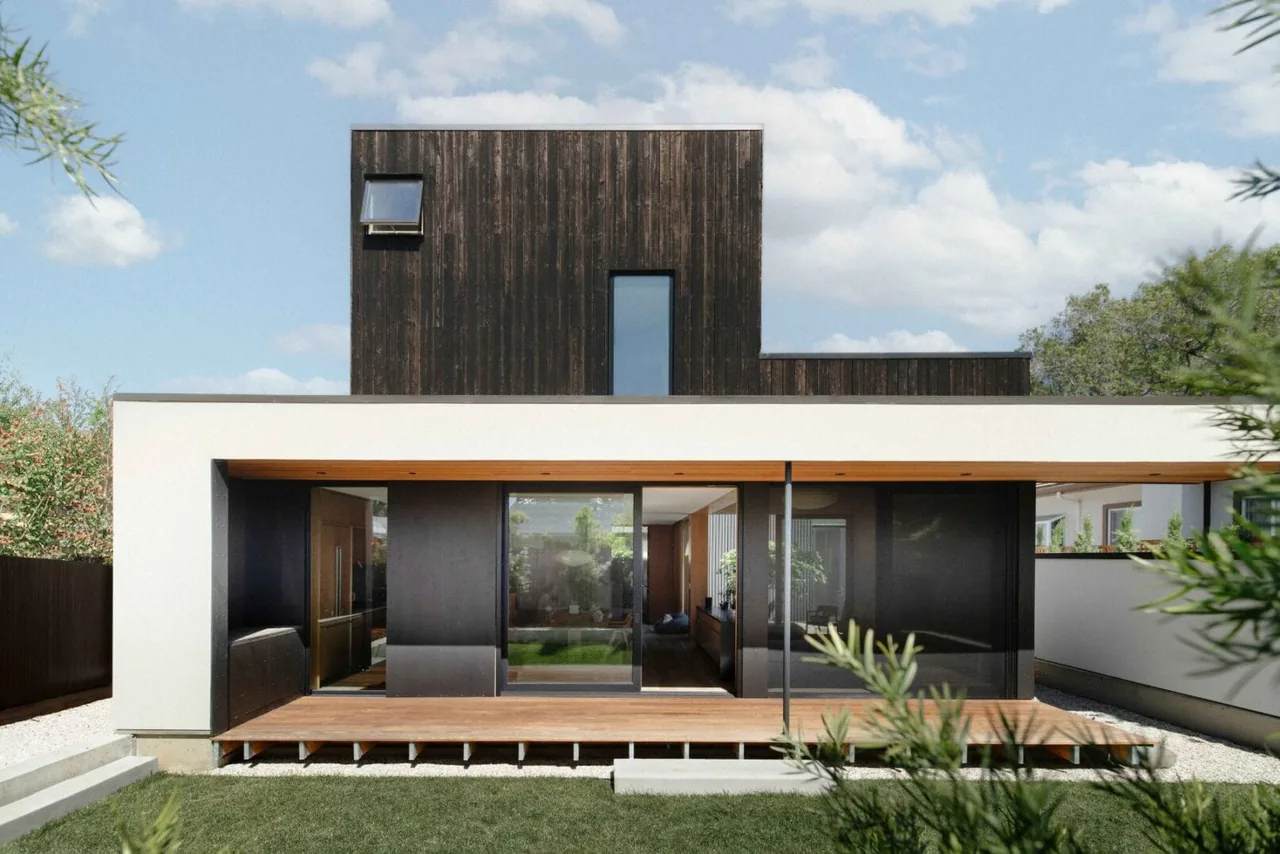 The Cupertino Courtyard House features a dark wood second story above a white and black ground floor with sliding glass doors to a wooden deck.