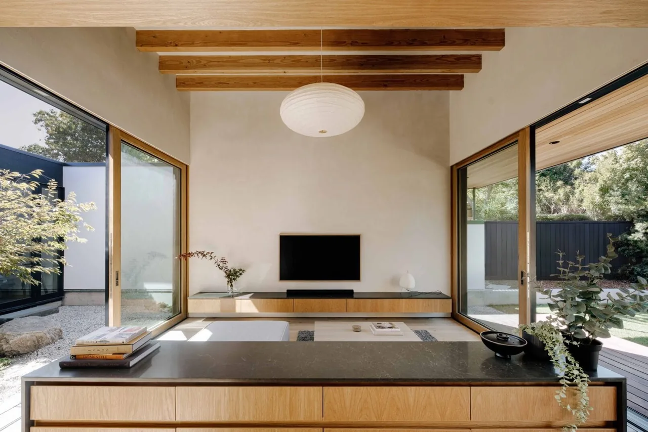 Living space featuring wood ceiling beams and wide glass sliding doors opening to an outdoor area.