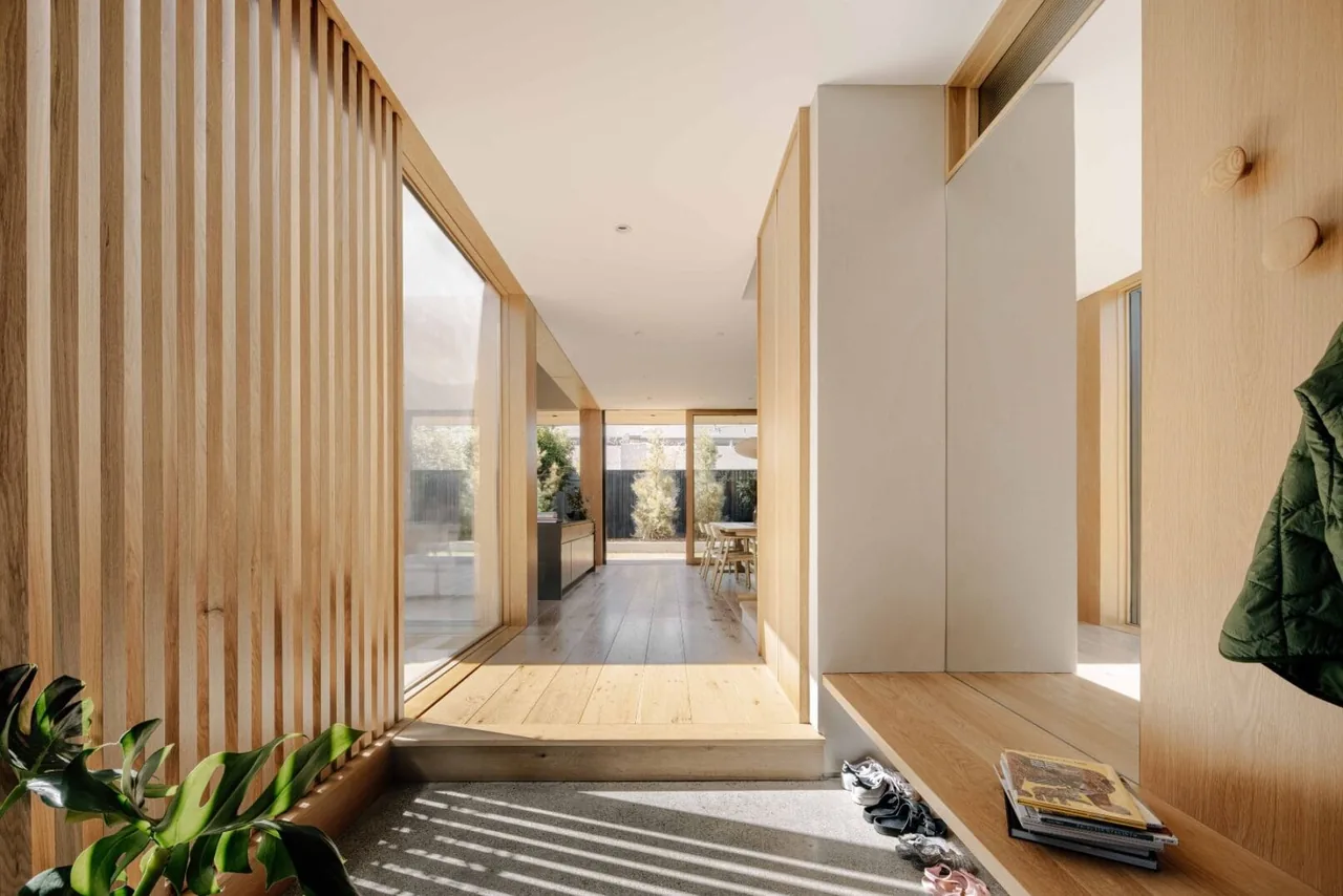 Entryway features vertical wood slats, a built-in bench, and transitions from concrete slab floor to wood.
