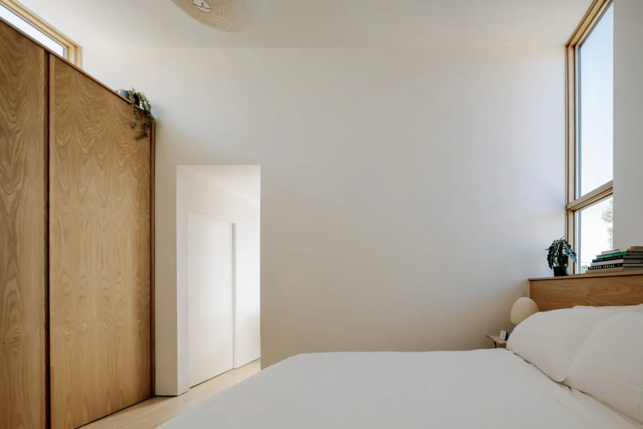Cupertino Courtyard House bedroom with wood closet, large windows, and simple white bedding by SHED Architecture & Design.